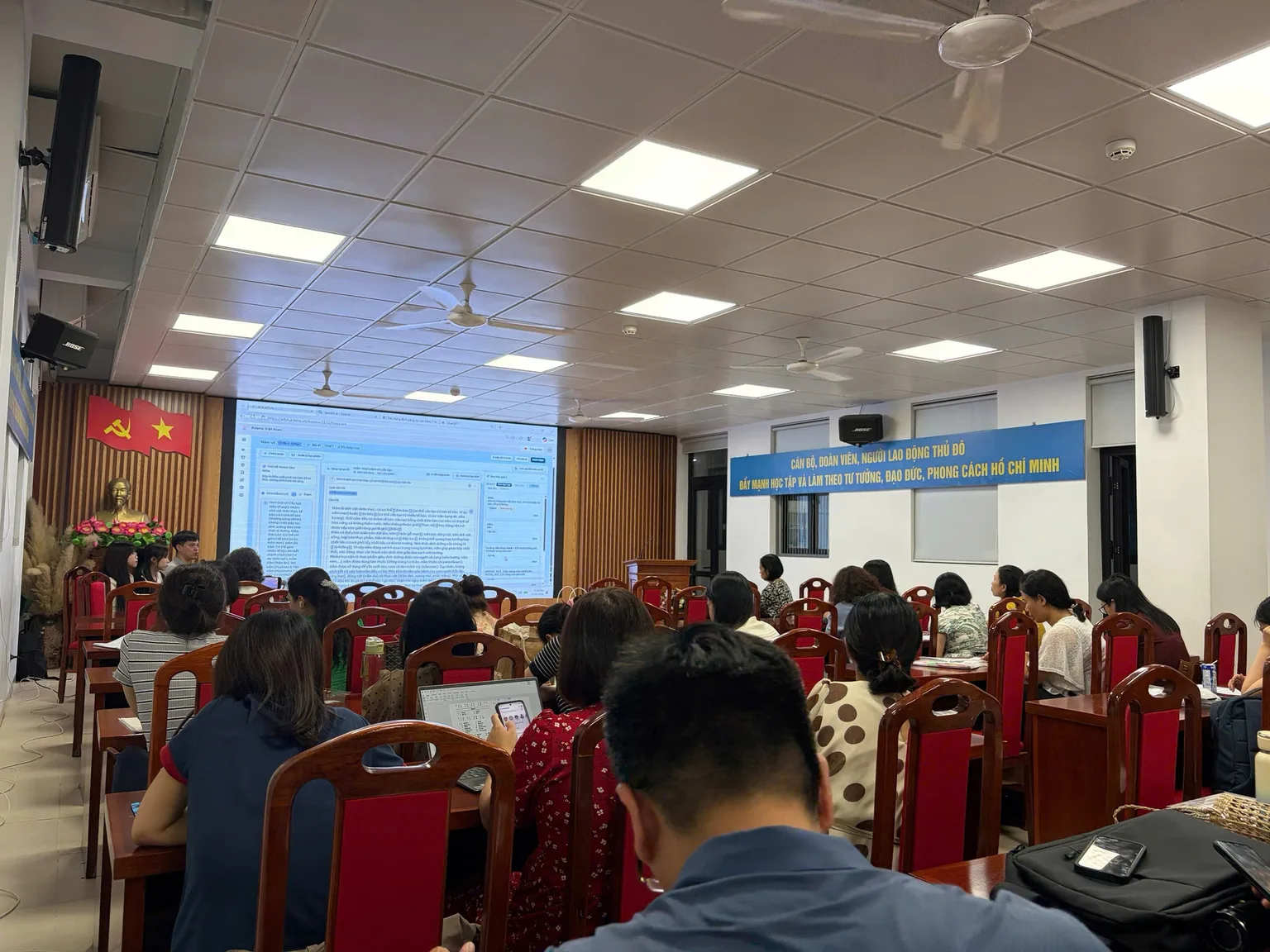 Hội trường với các thầy cô theo dõi phần trình bày trên màn chiếu